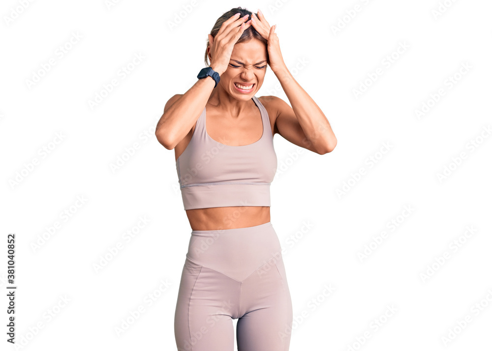Beautiful caucasian woman wearing sportswear suffering from headache desperate and stressed because pain and migraine. hands on head. Beautiful caucasian woman wearing sportswear suffering from headache desperate and stressed because pain and migraine. hands on head.