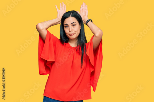 Beautiful young woman wearing casual clothes doing bunny ears gesture with hands palms looking cynical and skeptical. easter rabbit concept.