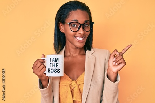 Foto Young african american woman drinking mug of coffe with i am the boss message sm