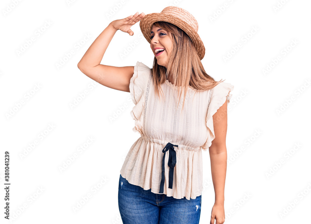 Young beautiful woman wearing summer hat and t-shirt very happy and smiling looking far away with hand over head. searching concept. Young beautiful woman wearing summer hat and t-shirt very happy and smiling looking far away with hand over head. searching concept.