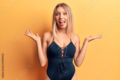 Young beautiful blonde girl wearing swimwear celebrating victory with happy smile and winner expression with raised hands