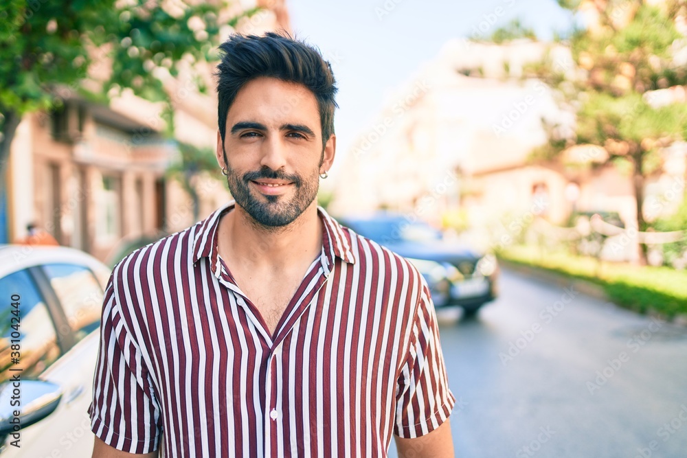 Fototapeta premium Young handsome hispanic man with beard smiling happy outdoors