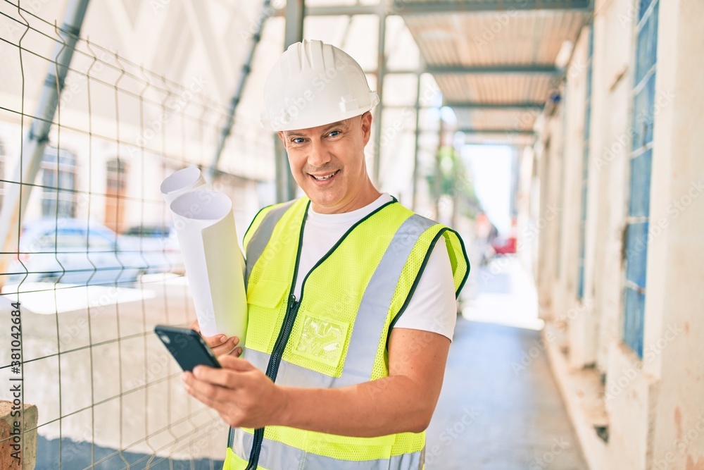 Middle age architect man using smartphone and holding blueprints at the city. Middle age architect man using smartphone and holding blueprints at the city.