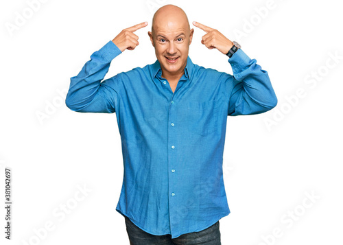 Middle age bald man wearing casual clothes smiling pointing to head with both hands finger, great idea or thought, good memory
