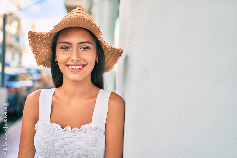 Young latin girl wearing summer style and smiling happy leaning on the wall.