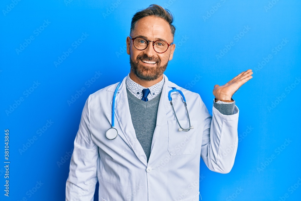 Handsome middle age man wearing doctor uniform and stethoscope smiling cheerful presenting and pointing with palm of hand looking at the camera. Handsome middle age man wearing doctor uniform and stethoscope smiling cheerful presenting and pointing with palm of hand looking at the camera.