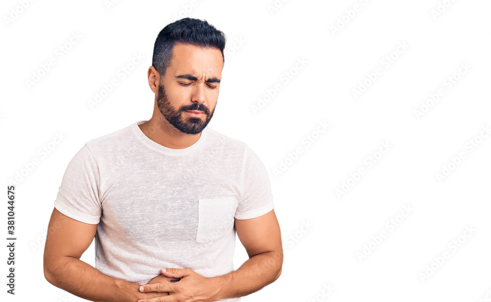 Young hispanic man wearing casual clothes with hand on stomach because indigestion, painful illness feeling unwell. ache concept. Young hispanic man wearing casual clothes with hand on stomach because indigestion, painful illness feeling unwell. ache concept.
