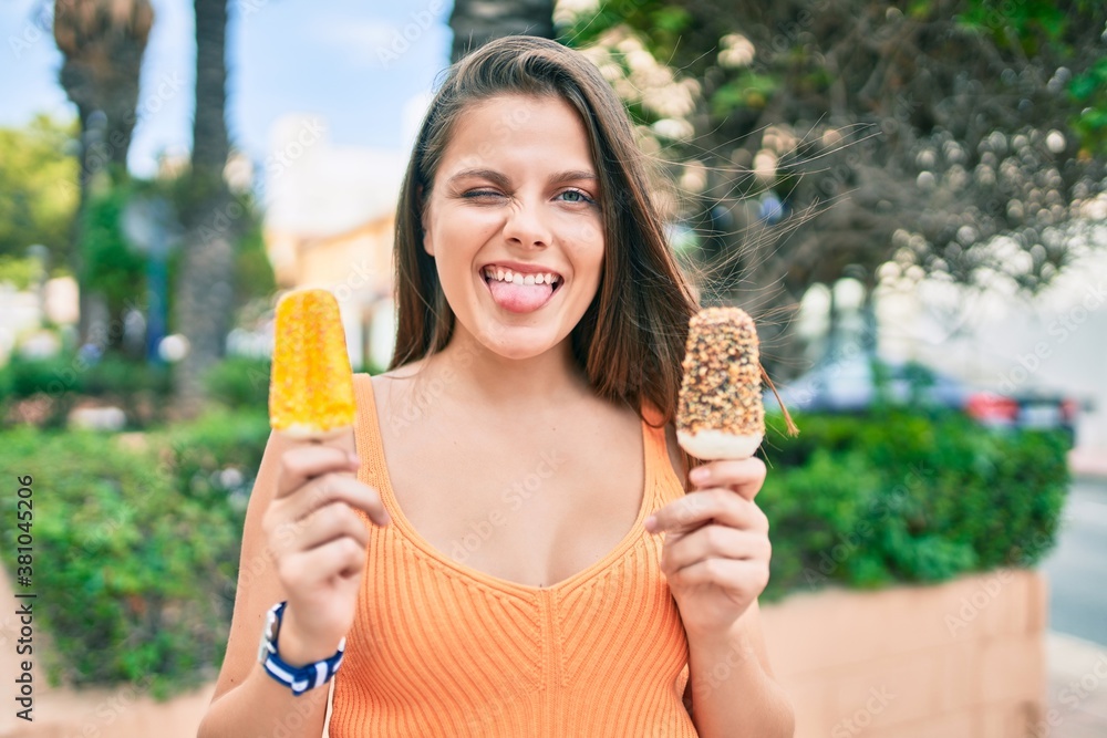 Young middle east girl bitting tongue and winking holding ice cream at the city. Young middle east girl bitting tongue and winking holding ice cream at the city.