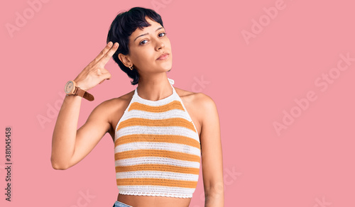 Obraz na plátne Young brunette woman with short hair wearing casual clothes shooting and killing oneself pointing hand and fingers to head like gun, suicide gesture