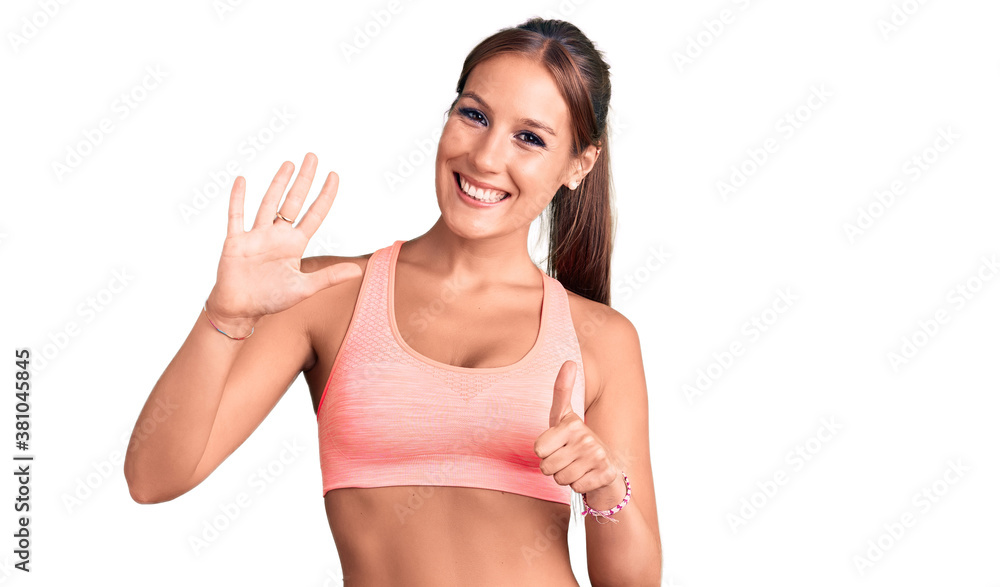 Young beautiful hispanic woman wearing sportswear showing and pointing up with fingers number six while smiling confident and happy. Young beautiful hispanic woman wearing sportswear showing and pointing up with fingers number six while smiling confident and happy.