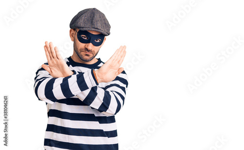 Young handsome man wearing burglar mask rejection expression crossing arms doing negative sign, angry face © Krakenimages.com