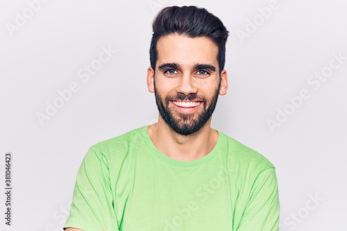 Young handsome man with beard wearing casual t-shirt happy face smiling with crossed arms looking at the camera. positive person.