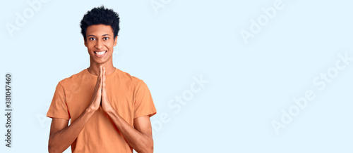 Young african american man wearing casual clothes praying with hands together asking for forgiveness smiling confident. © Krakenimages.com