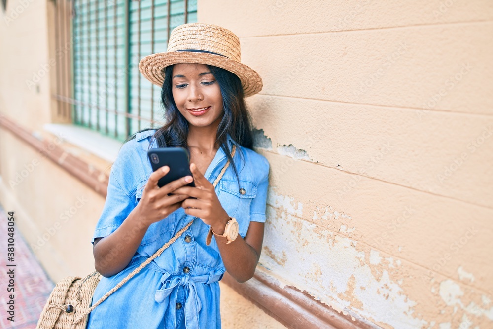 Young indian woman leaning on the wall using smartphone at the city