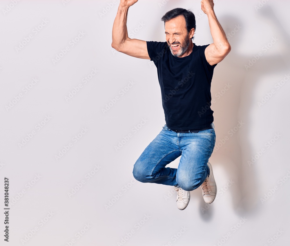 Middle age handsome man wearing casual clothes smiling happy. Jumping with smile on face doing winner gesture with fists up over isolated white background Middle age handsome man wearing casual clothes smiling happy. Jumping with smile on face doing winner gesture with fists up over isolated white background