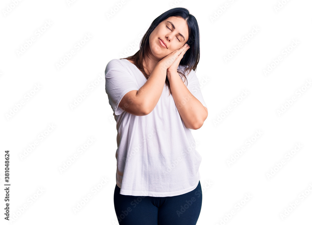 Young beautiful brunette woman wearing casual t-shirt sleeping tired dreaming and posing with hands together while smiling with closed eyes. Young beautiful brunette woman wearing casual t-shirt sleeping tired dreaming and posing with hands together while smiling with closed eyes.
