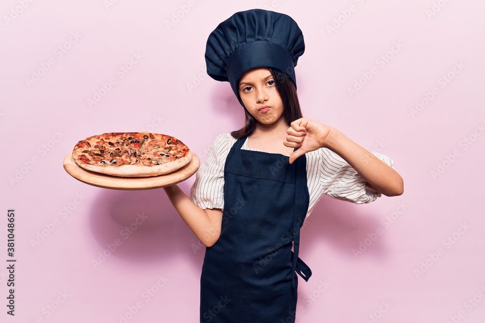 Beautiful child girl wearing cooker uniform holding italian pizza with angry face, negative sign showing dislike with thumbs down, rejection concept Beautiful child girl wearing cooker uniform holding italian pizza with angry face, negative sign showing dislike with thumbs down, rejection concept