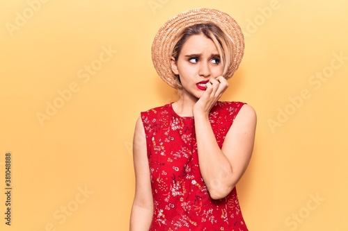 Young beautiful blonde woman wearing summer hat looking stressed and nervous with hands on mouth biting nails. anxiety problem.