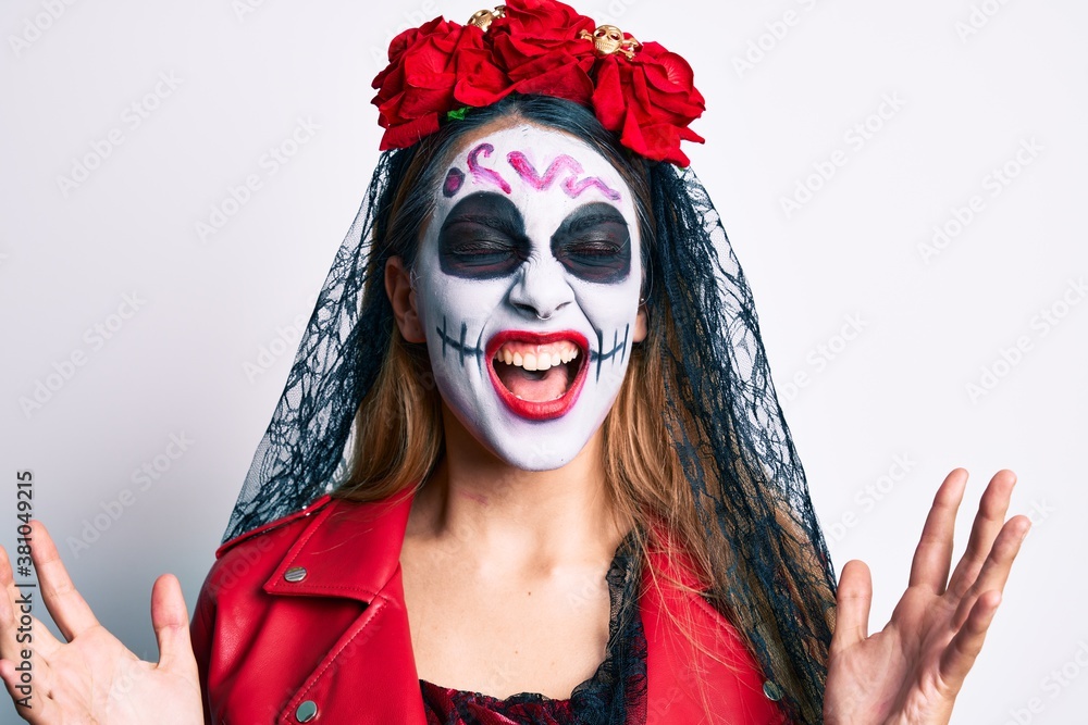 Woman wearing day of the dead costume over white crazy and mad shouting and yelling with aggressive expression and arms raised. frustration concept.