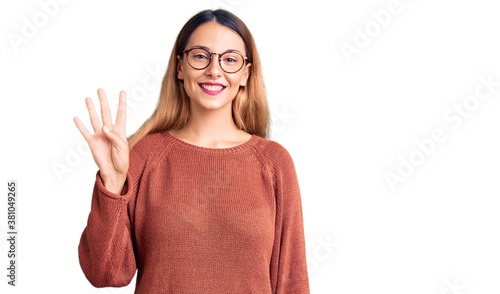 Beautiful young woman wearing casual clothes and glasses showing and pointing up with fingers number four while smiling confident and happy. © Krakenimages.com