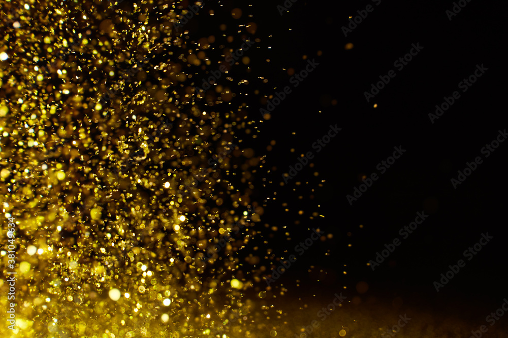 Sparkling golden glittering effect isolated on black background.