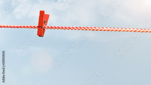 Four red clothespins on a red and white rope isolated on a white background.