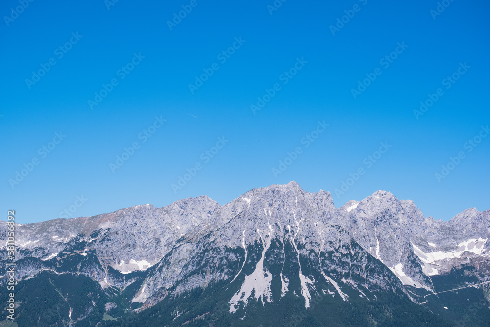 Bergkette vor einem blauen Himmel. Segelflugzeuge kreisen weit entfernt