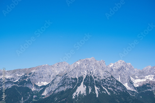 Bergkette vor einem blauen Himmel. Segelflugzeuge kreisen weit entfernt