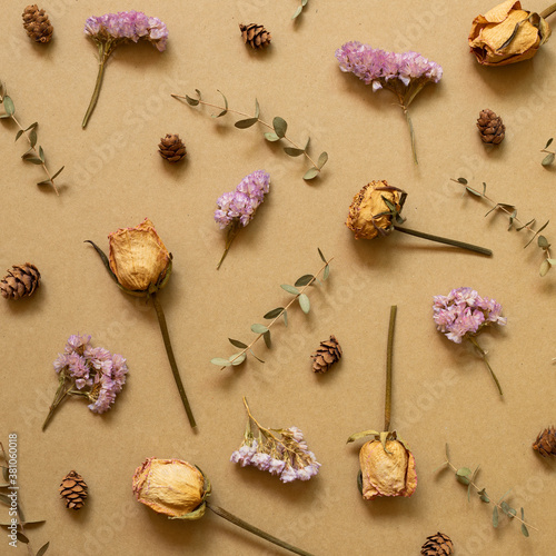 Autumn dry plant pattern background. Dry rose, statice flowers, eucalyptus leaves, pine cones on brown kraft paper background. flat lay, top view