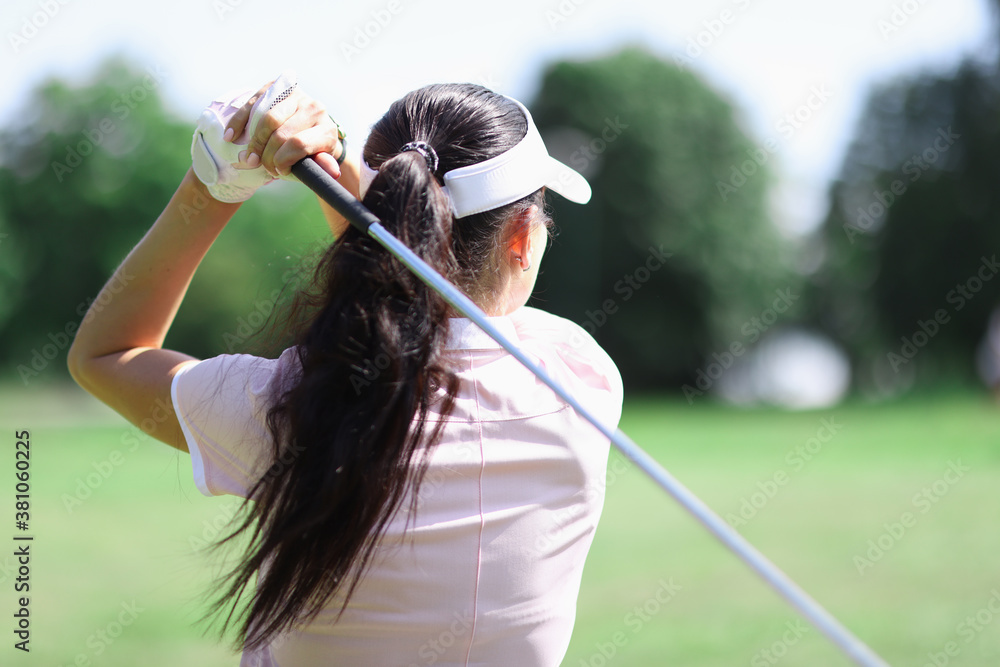 Female golfer stands with her back and holds golf club in her hands. Golf concept Female golfer stands with her back and holds golf club in her hands. Golf concept