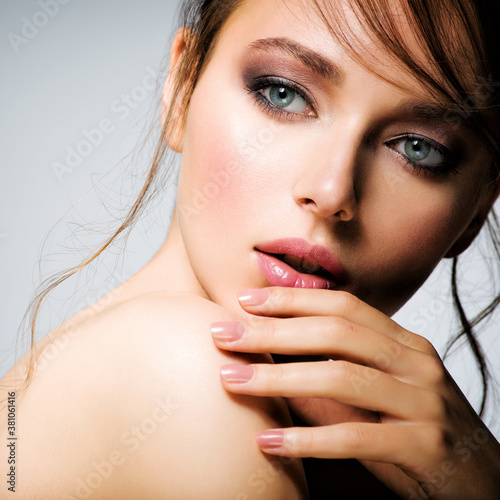 Closeup face of young beautiful woman with a healthy clean skin.  Pretty woman with bright  makeup of eyes. Beautiful white girl. Portrait of a beautiful girl with a long curl of hair hanging down.