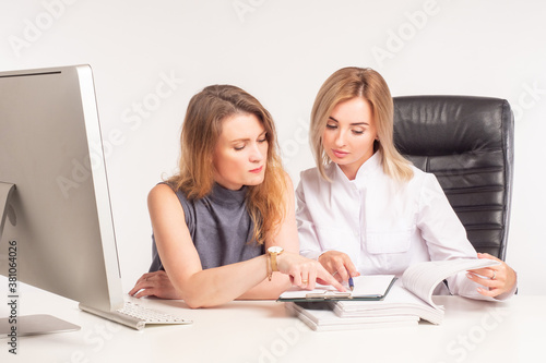 Two girls check documents. Women at the Desk look through documents. Auditor check. Two serious women at work. Office work.