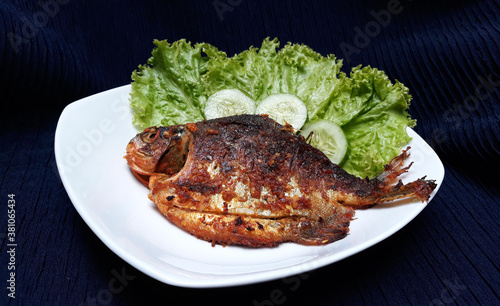grilled pomfret (Ikan Bawal Bakar) on a white plate 