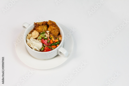 Soto Betawi. Traditional Chicken soup from Betawi, Jakarta. Served in a white bowl on white background