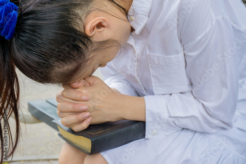 Woman hands praying with a bible in her knees outdoors