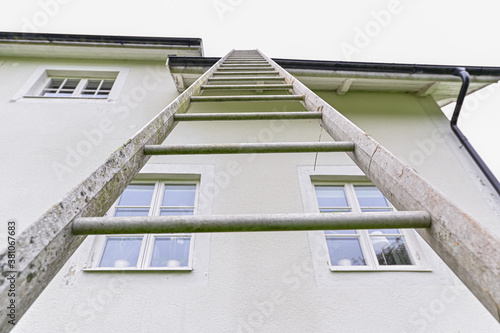 metal ladder standing high against roof gutter