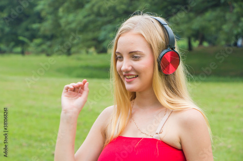Beautiful young woman with head phone listening music in the park