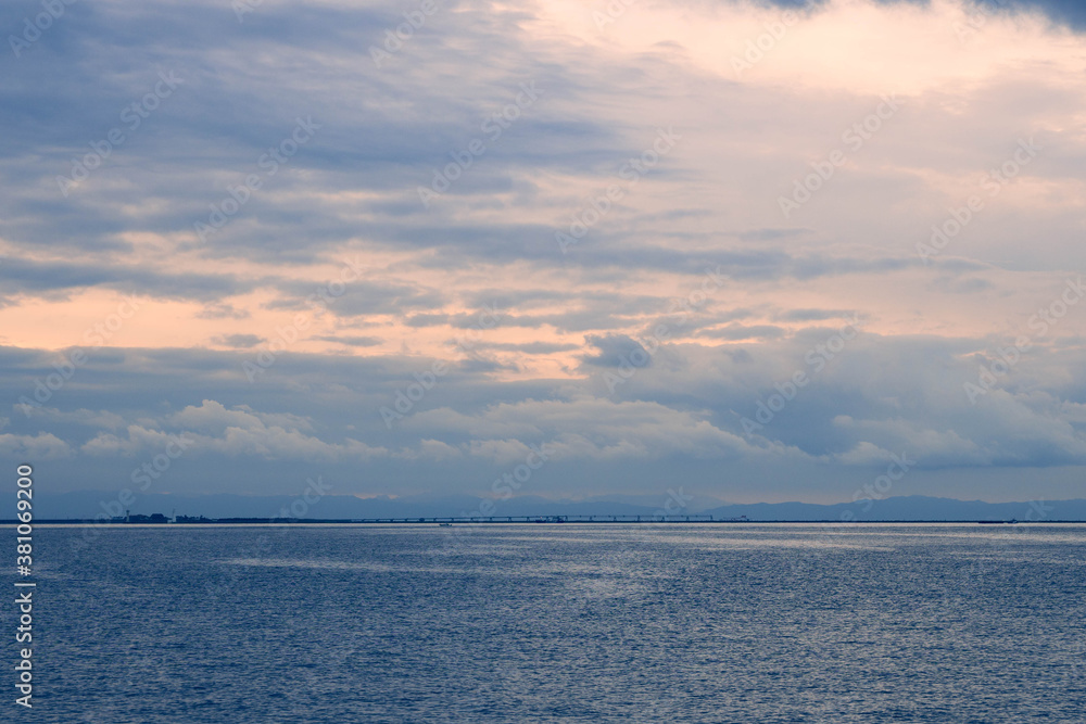 夜明けの大阪湾、神戸新港突堤から雲に覆われた空から朝日が覗く。