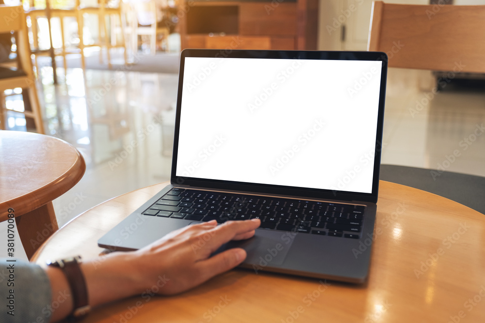 Mockup image of a hand touching on laptop computer touchpad with blank white desktop screen on wooden table Mockup image of a hand touching on laptop computer touchpad with blank white desktop screen on wooden table