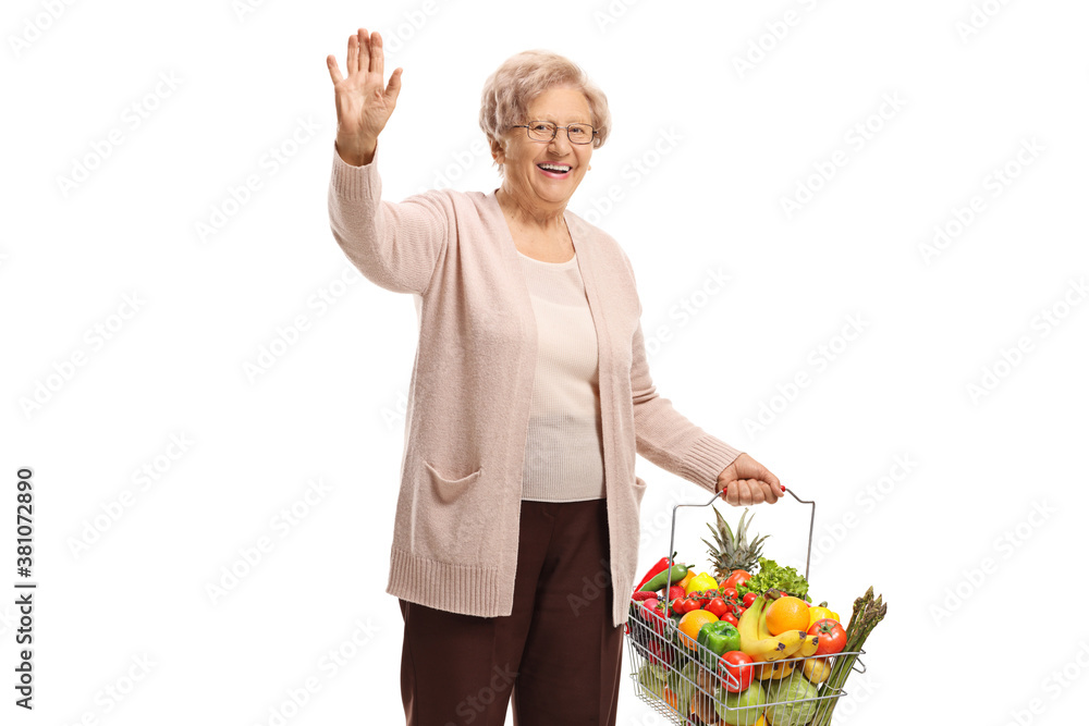 Older woman with fruits and vegetables in a shopping basket waving Older woman with fruits and vegetables in a shopping basket waving