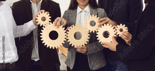Company employees joining gearwheels as metaphor for effective business management and teamwork