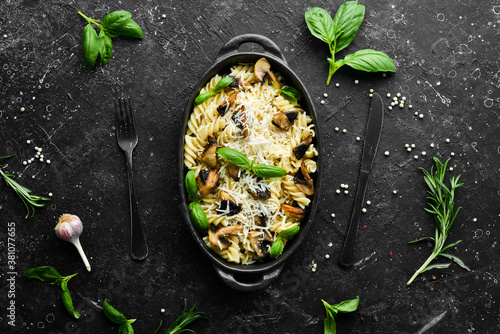 Pasta with mushrooms, parmesan cheese and basil in a black pan. Top view.