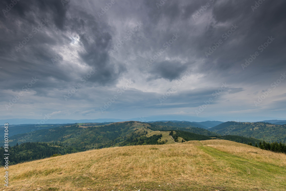 Landscape view from the top of the mountain in the Carpathian mountains, Romania, dramatic storm clouds in the background.