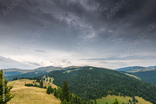 Landscape view from the top of the mountain in the Carpathian mountains, Romania, dramatic storm clouds in the background. © Alpar