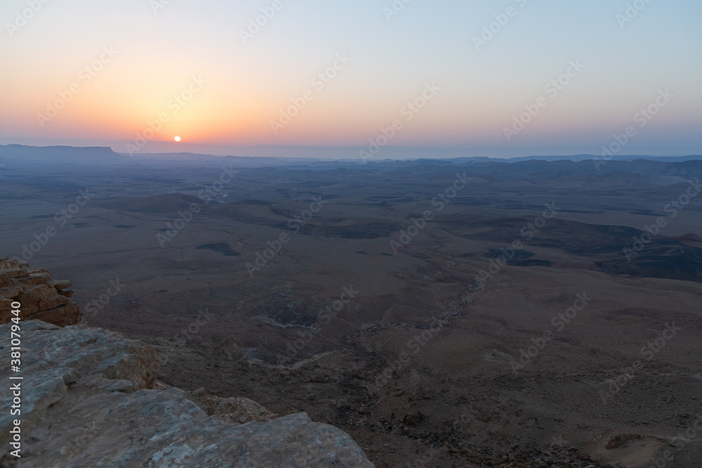 a flaming cloudless sunrise showing the vastness and geology of the makhtesh ramon crater in the negev desert in israel