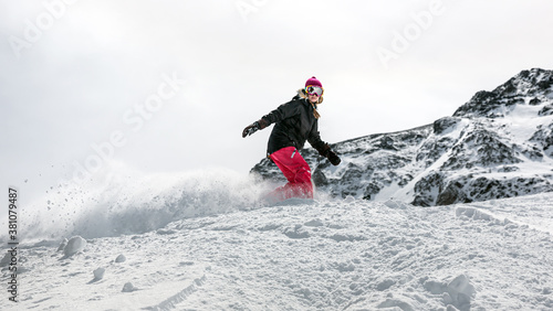 Young woman snowboarder in motion on snowboard in mountains photo