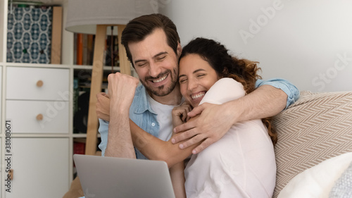 Excited young couple feel euphoric winning online lottery on laptop. Happy overjoyed millennial man and woman triumph get pleasant email or good news message notification on computer. Luck concept.