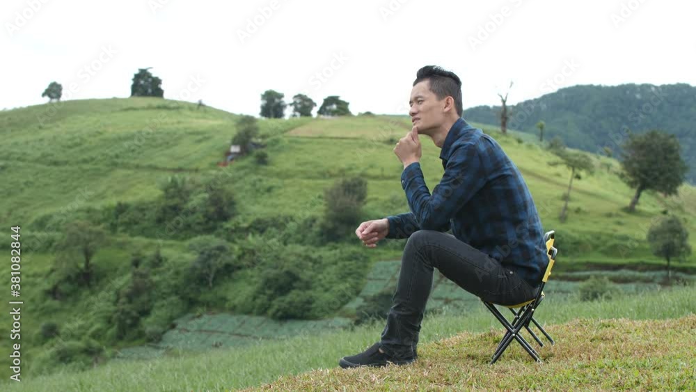 Asian man Sit and admire the view on the top of the mountain in the morning Asian man Sit and admire the view on the top of the mountain in the morning