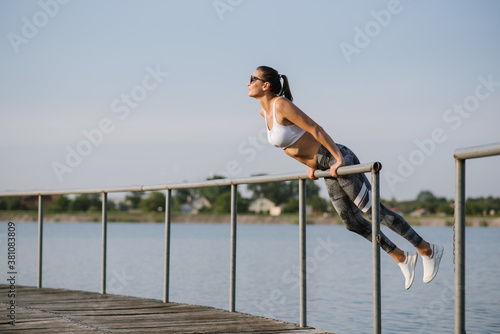 Young slim fit woman doing sport exercise outdoors in the park at the sunny day