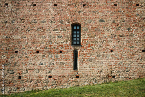 old medieval castle brick wall with a hole and window